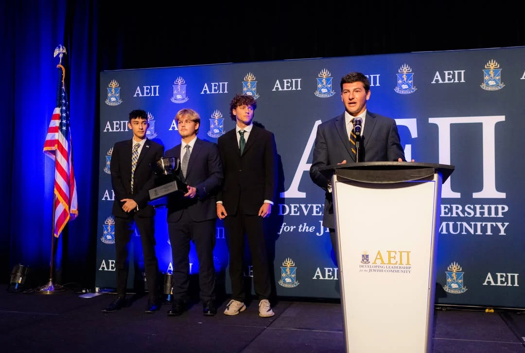 Three Sigma Beta brothers holding the Louis Sherr Chapter of the Year trophy on stage at the AEPi International Convention