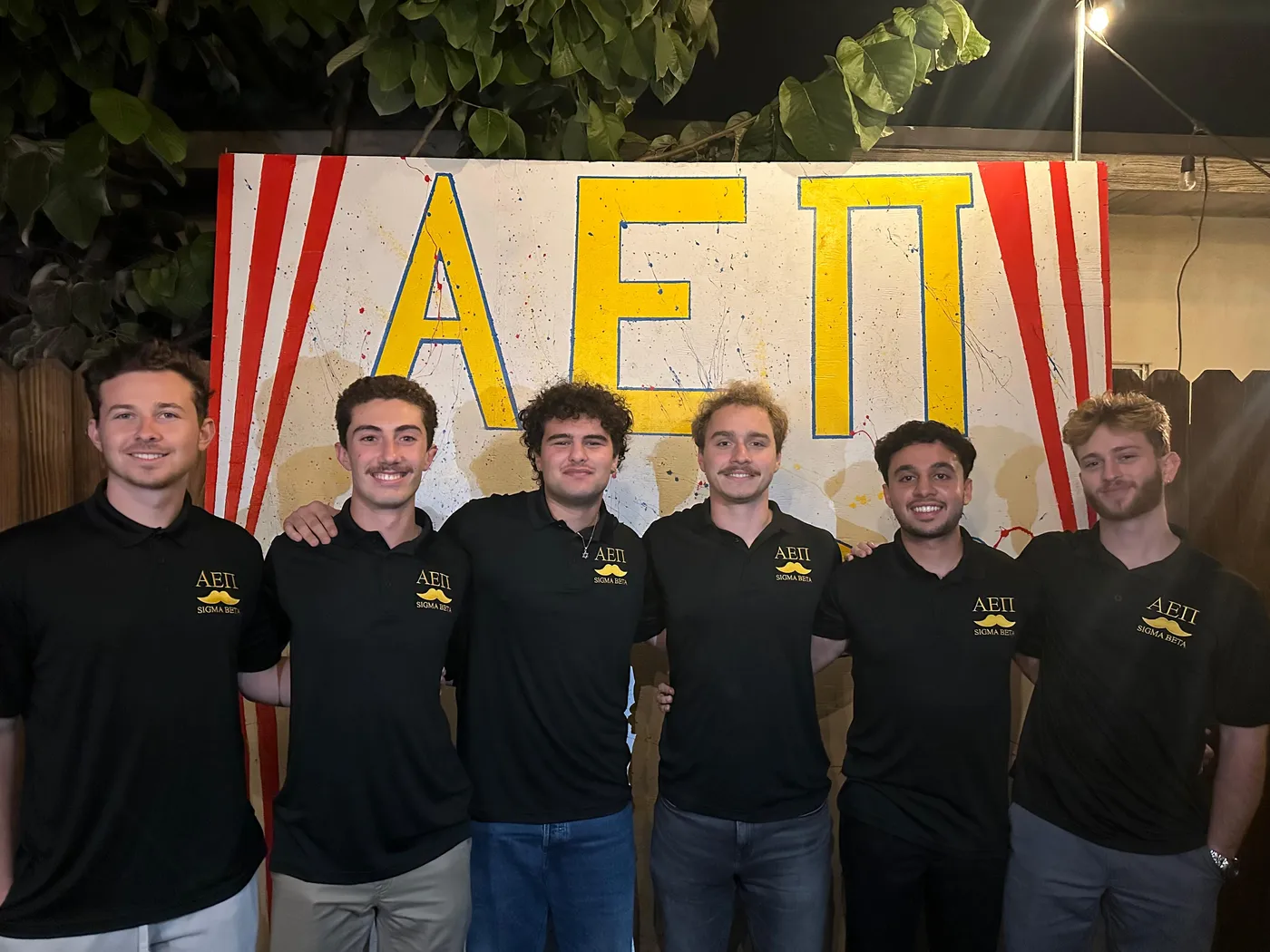 Brothers in front of the chapter banner at a philanthropy event